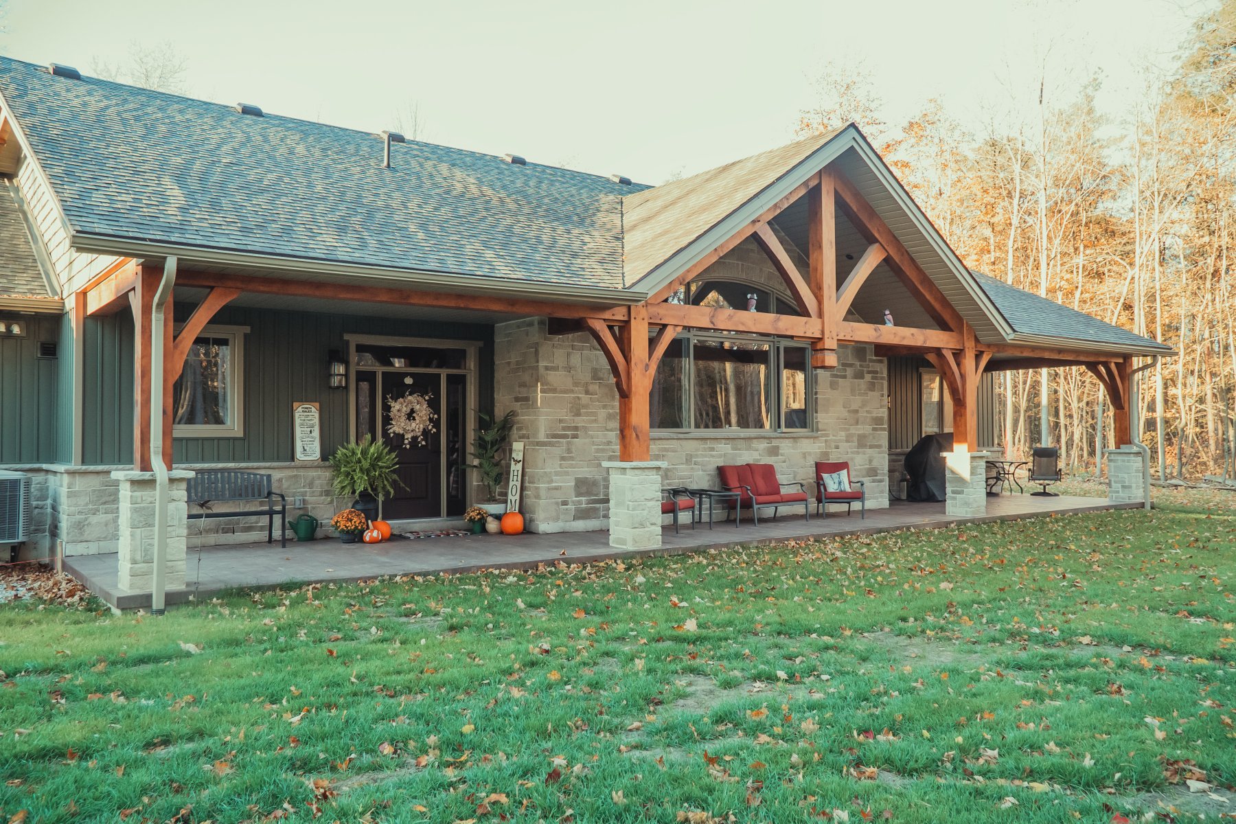 Lang's General Contracting — custom timber-frame home with a covered stone porch at golden hour